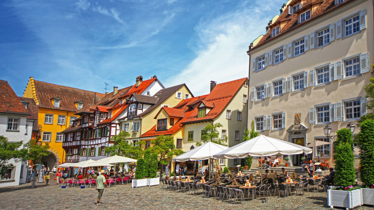 Marktplatz mit bunten Fachwerk- und Bürgerhäusern und Sonnenschirmen